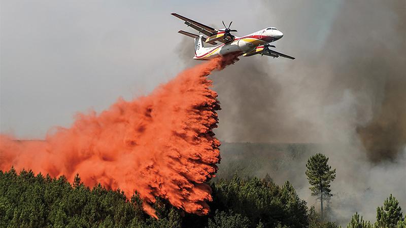 aircraft releasing orange flame retardant over forest